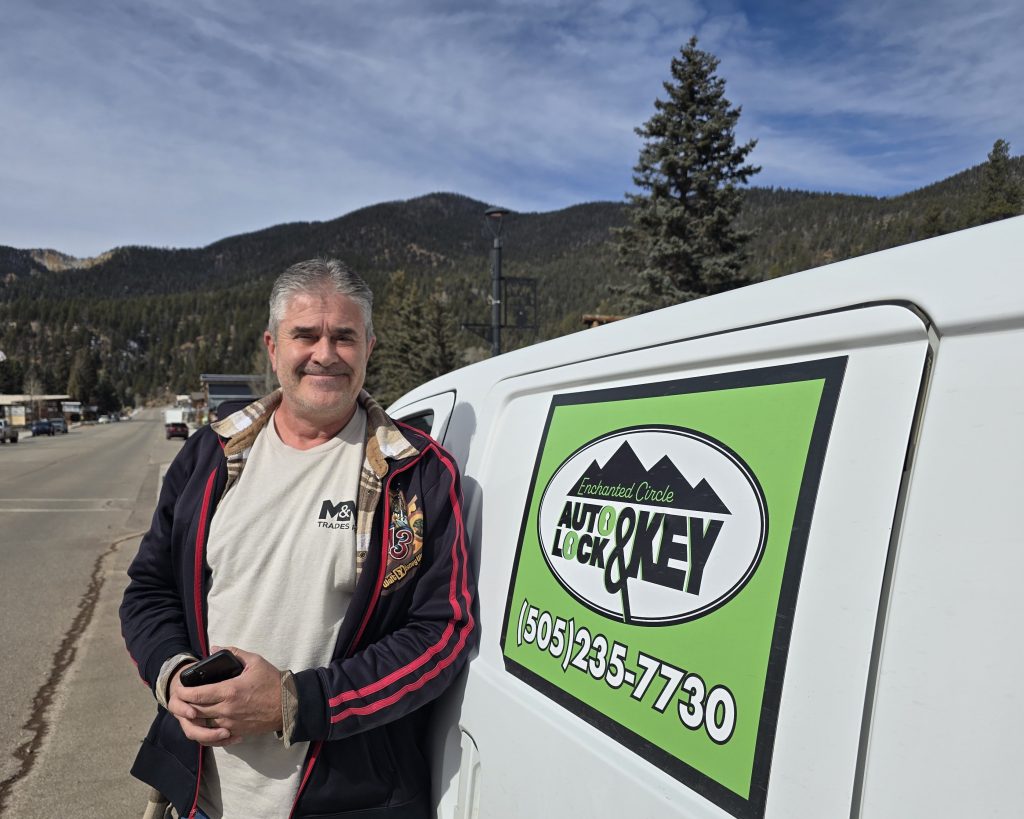 John Foster stands beside the Enchanted Circle Auto Lock & Key service van with logo and phone number visible.